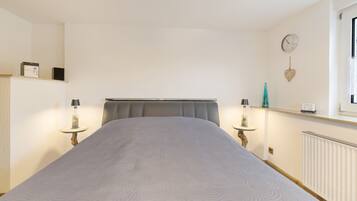 Ein Schlafzimmer mit einem Bett, Nachttischen, einer Uhr und einem Fenster.