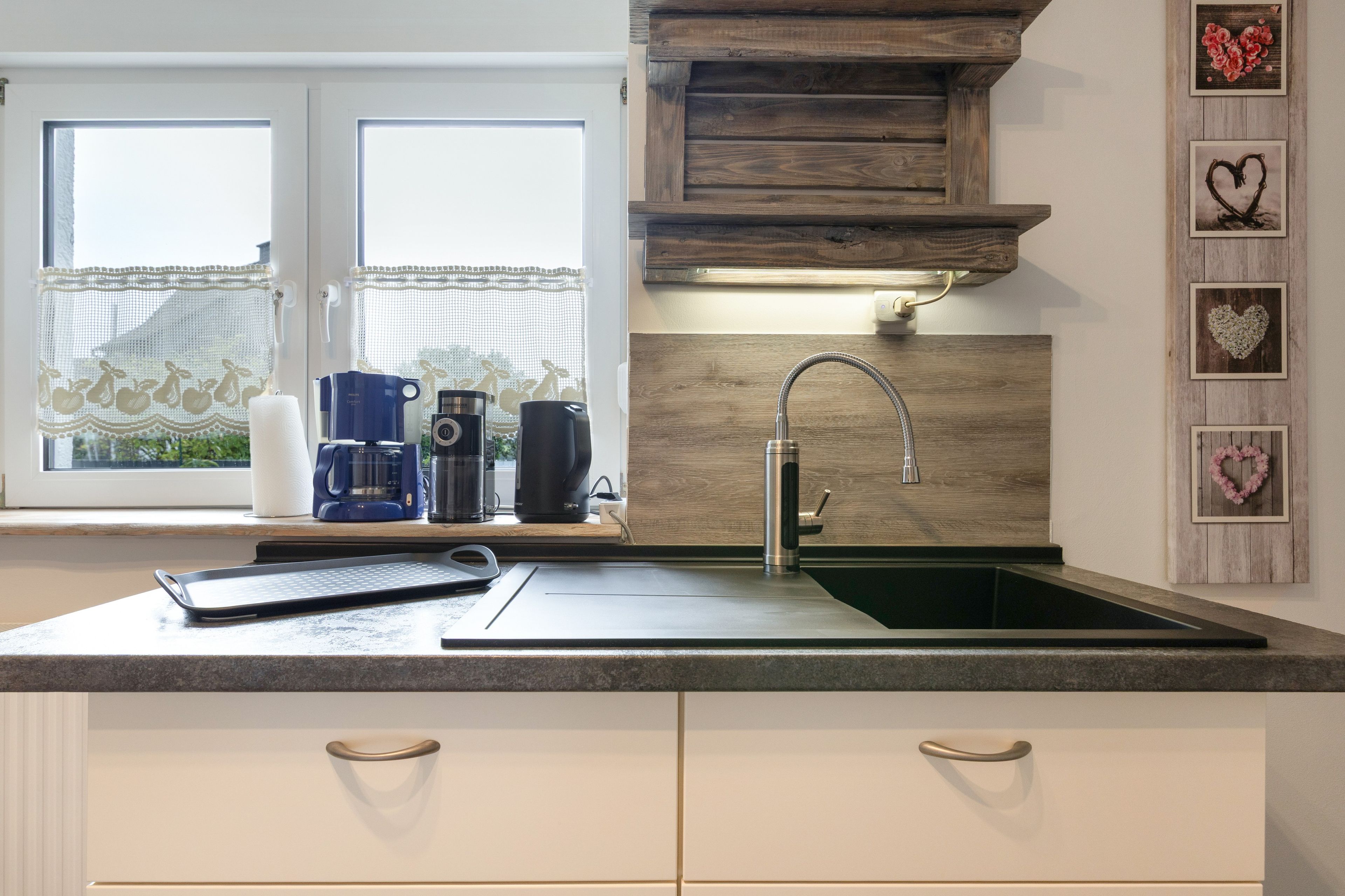 A modern kitchen with a built-in sink, a coffee maker, and a kettle on the counter.