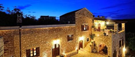 A stone building with multiple levels, arched doorways, and a courtyard with stone paving.
