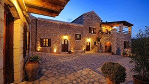A stone building with multiple doors and windows, a covered outdoor area, and potted plants.
