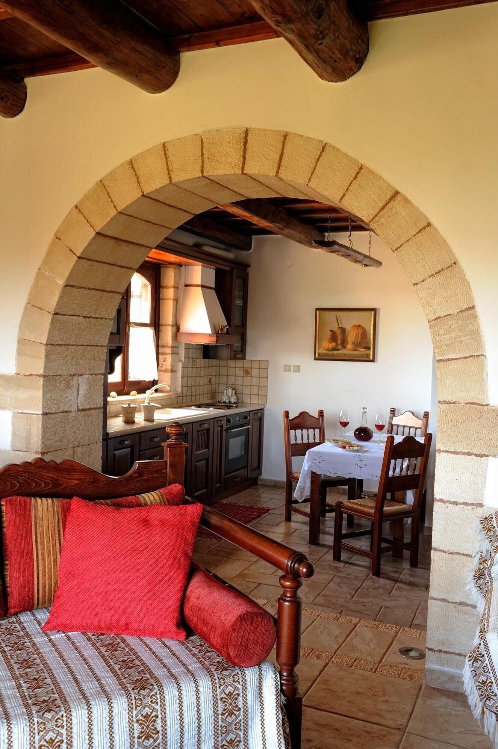 A cozy room with a bed, a dining table with chairs, and a kitchen area visible through an archway.