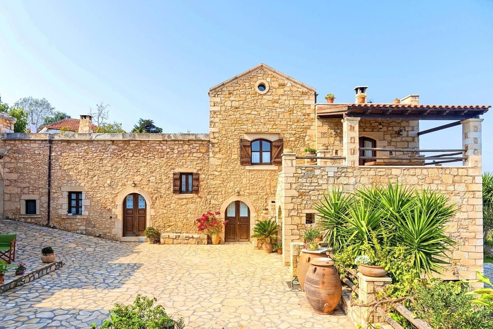 Un edificio in pietra con un cortile, portali ad arco e vasi di piante.