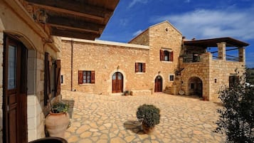A stone building with a courtyard, wooden shutters, and a small garden.