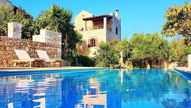 A swimming pool with lounge chairs and a stone wall.