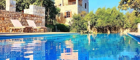 A swimming pool with lounge chairs and a stone wall.