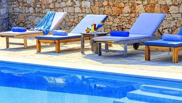 A poolside area with lounge chairs and a stone wall.