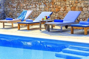 Ein Poolbereich mit Liegestühlen und einer Steinmauer.