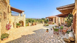 A stone courtyard with a patio area, outdoor seating, and potted plants.