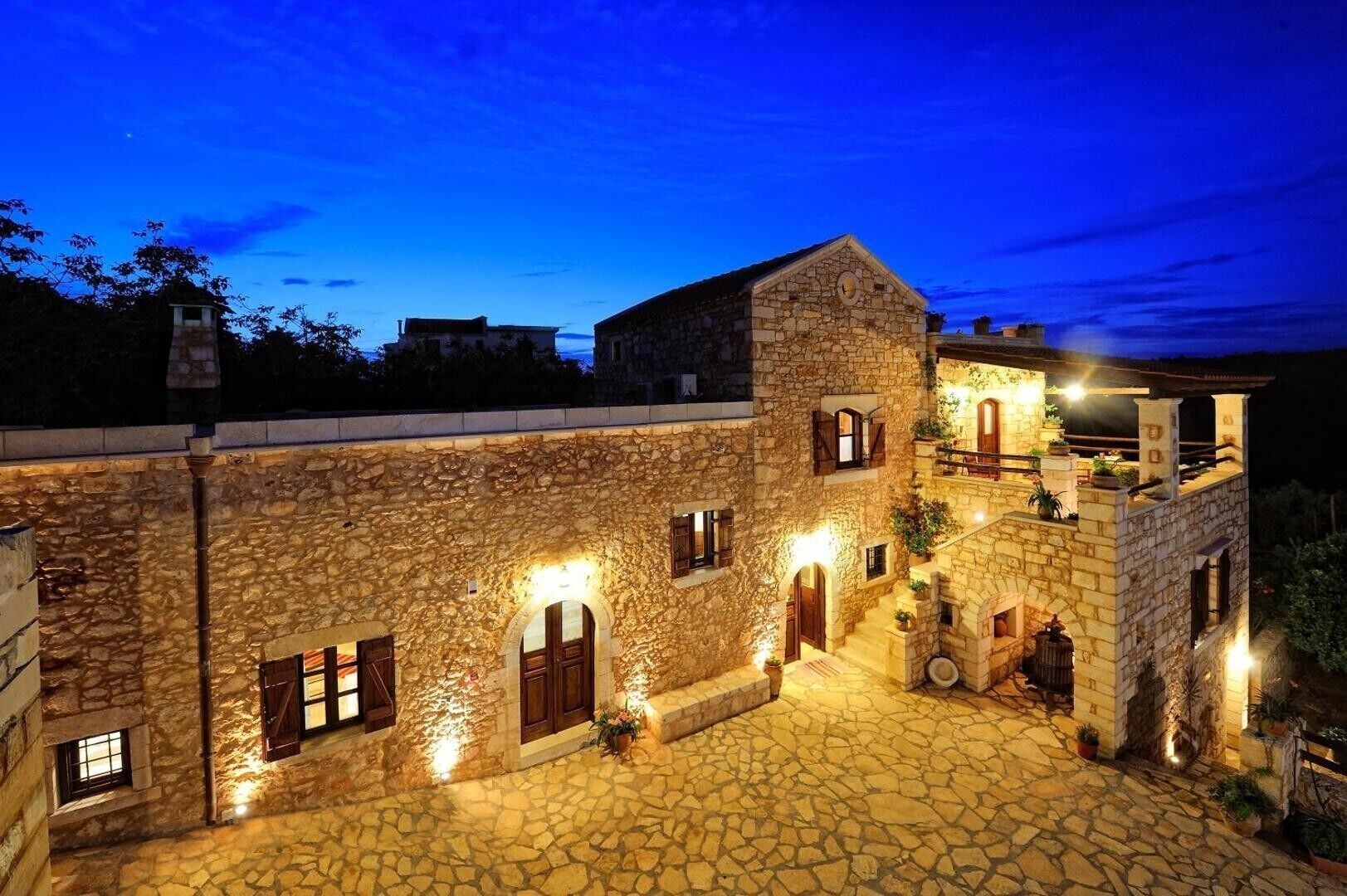 A stone building with multiple levels, arched doorways, and a courtyard with stone paving.