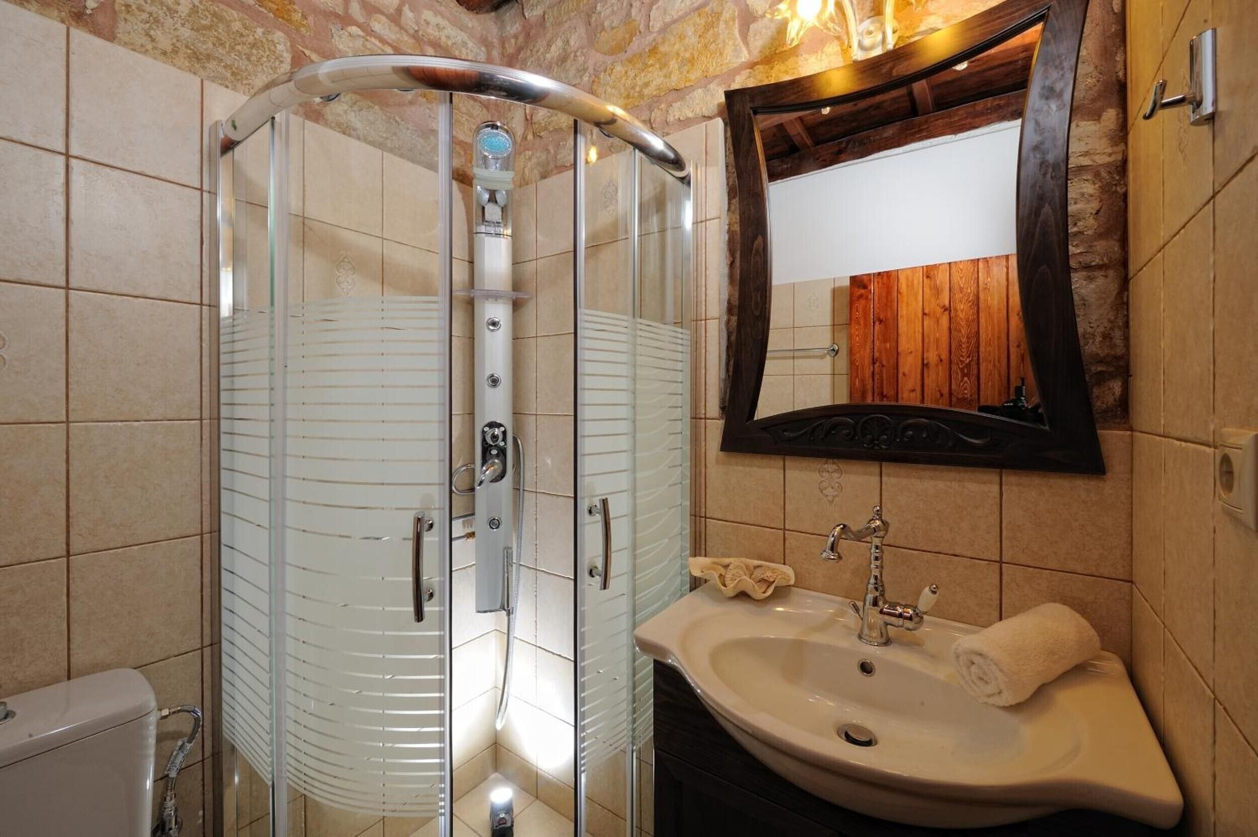 A bathroom with a glass-enclosed shower, a sink, and a mirror.
