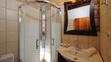 A bathroom with a glass-enclosed shower, a sink, and a mirror.