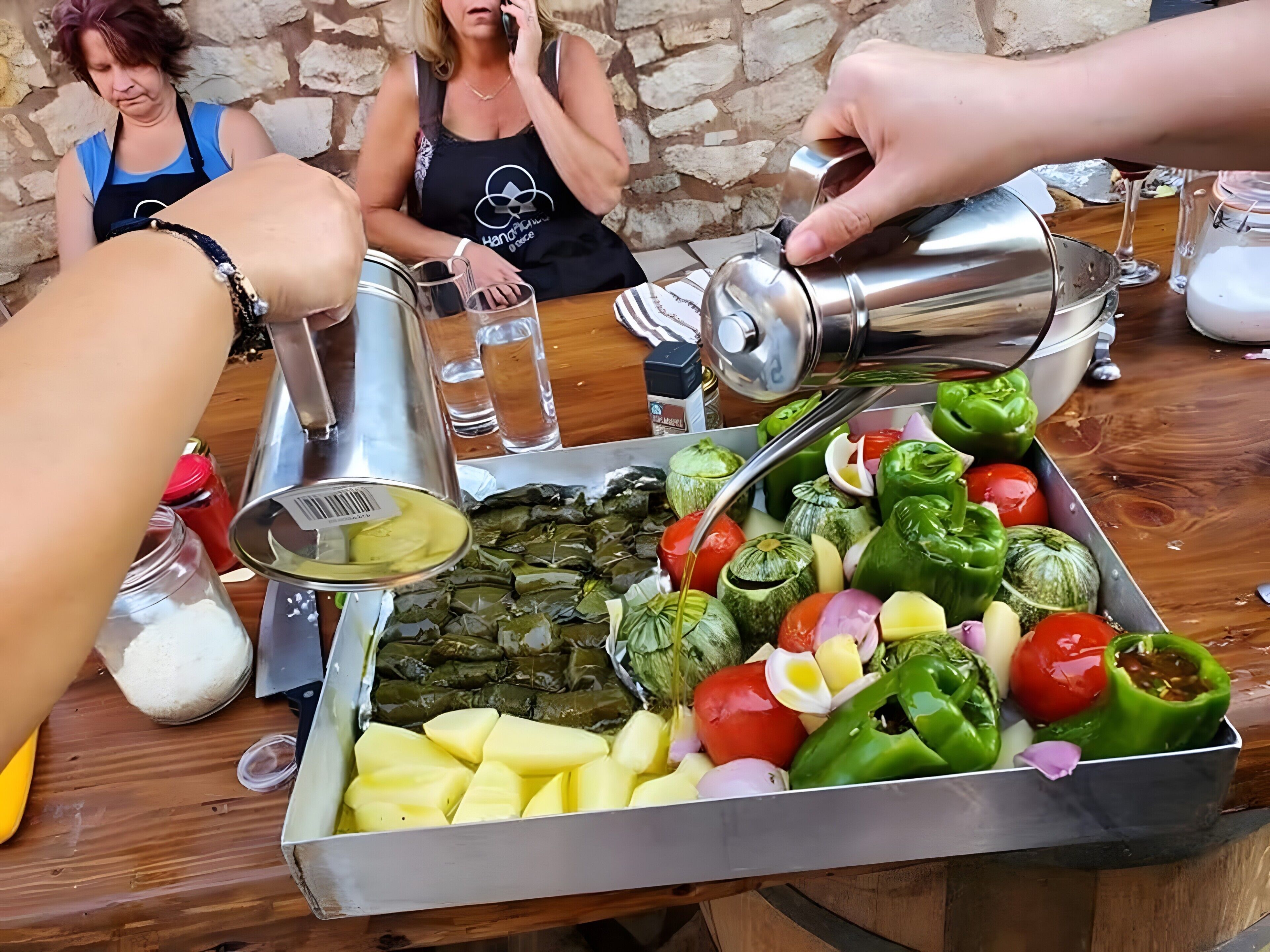A table with a variety of food items, including stuffed vegetables and a metal container being filled with a yellow liquid.