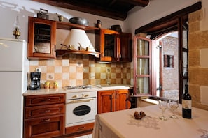 Une cuisine avec des meubles en bois, un fourneau et une fenêtre donnant sur l’extérieur.