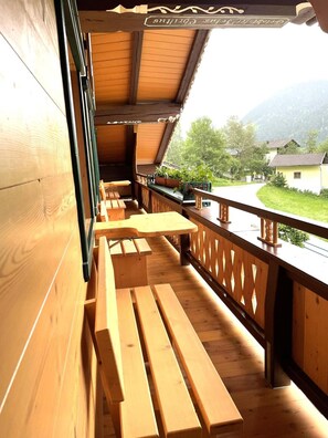 En træterrasse med bænke, med udsigt over et landligt landskab med huse og grøn vegetation.