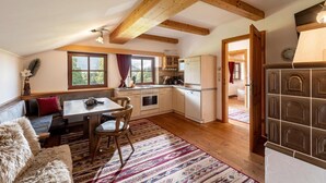 Una cocina acogedora con vigas de madera, un comedor con mesa y sillas, y vistas al exterior a través de amplios ventanales.