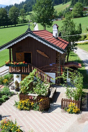 Ein Holzhaus mit rotem Dach und einer Holzveranda, mit einem Schild, auf dem 'FISCHERHUTTE' steht.