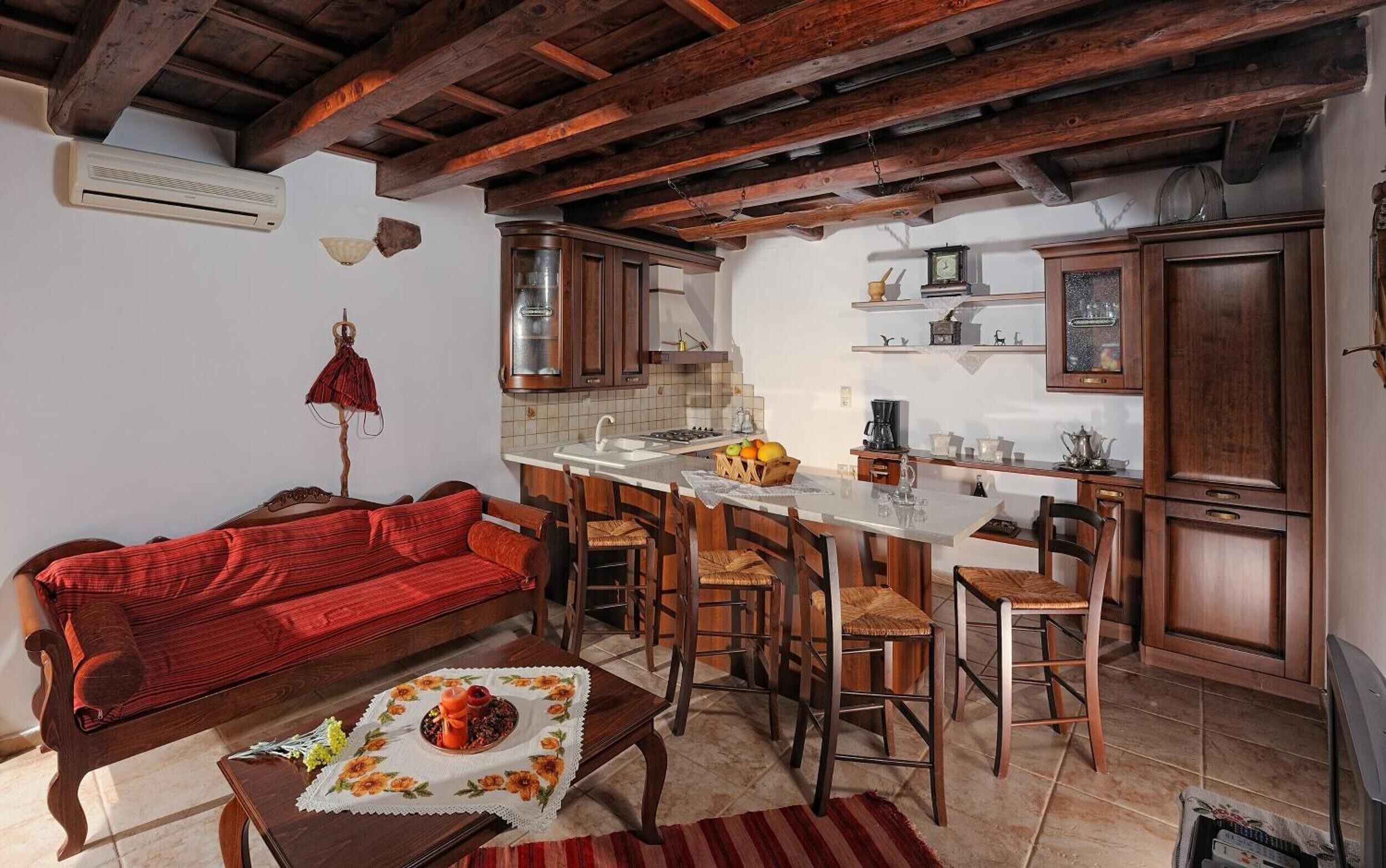 Une cuisine chaleureuse avec un plafond en bois, un canapé rouge et un coin repas avec des chaises en bois.
