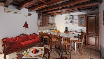 Une cuisine chaleureuse avec un plafond en bois, un canapé rouge et un coin repas avec des chaises en bois.