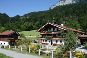 A traditional chalet with a balcony, surrounded by a garden with flowers and a wooden fence. - Apartment 'Hitscherhof - Abart' with Balcony and Wi-Fi (Söll)