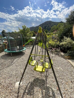 A playground with a swing set and a trampoline in a park with a mountainous backdrop. - Apartment Hitscherhof - Abart with Balcony and Wi-Fi (Söll)