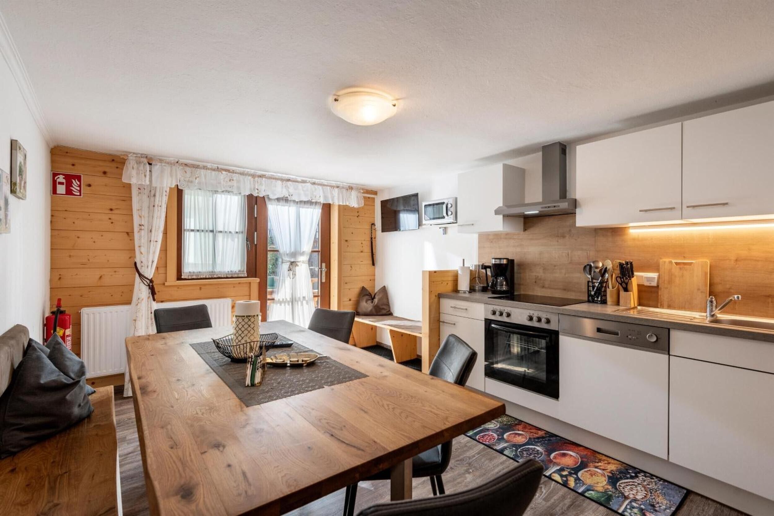 Una cocina compacta con estufa, horno, microondas y un pequeño comedor con mesa y sillas.