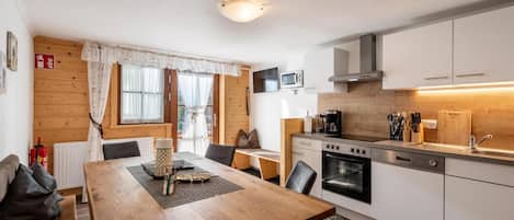 Una cocina compacta con estufa, horno, microondas y un pequeño comedor con mesa y sillas.