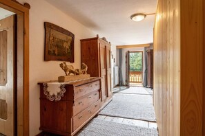 Ein Flur mit Holzausstattung, einem Gemälde und Blick auf einen Balkon.