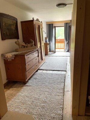 A room with a wooden dresser, a rug, a painting on the wall, and a view through a doorway to an outdoor balcony. - Apartment Hitscherhof - Abart with Balcony and Wi-Fi (Söll)