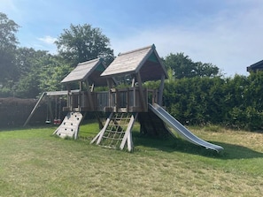 A wooden play structure with a slide and climbing area.