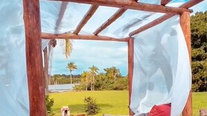 A wooden bed frame with a canopy, white bedding, and red and grey pillows.