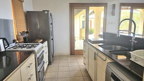 Eine Küche mit Gaskochfeld, Backofen, Kühlschrank und Spüle.