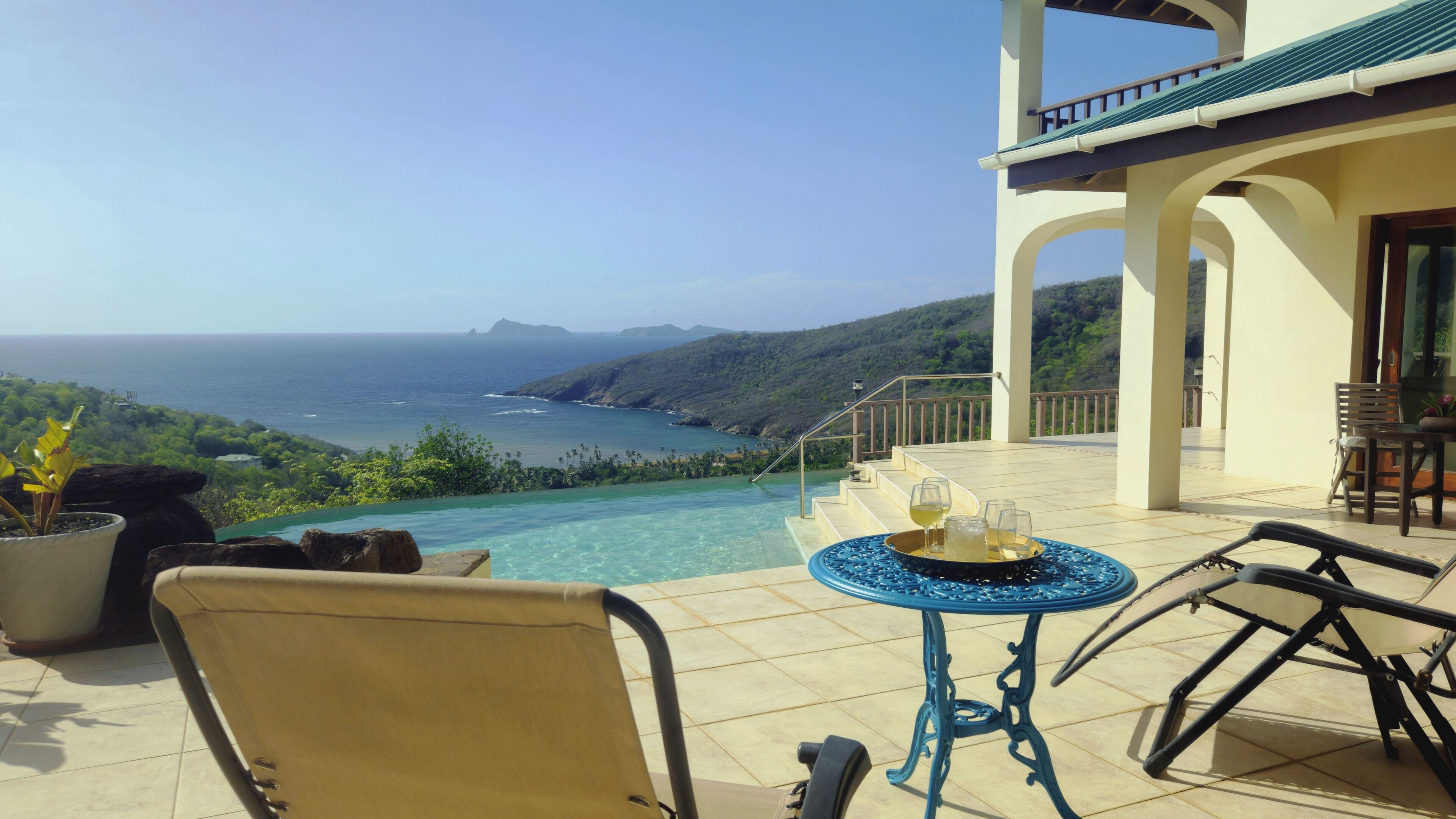 Eine Terrasse mit Blick auf das Meer, ein Tisch mit Gläsern und ein Stuhl.