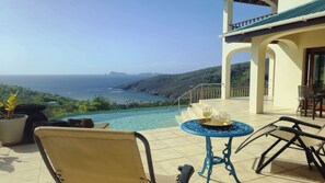 Eine Terrasse mit Blick auf das Meer, ein Tisch mit Gläsern und ein Stuhl.