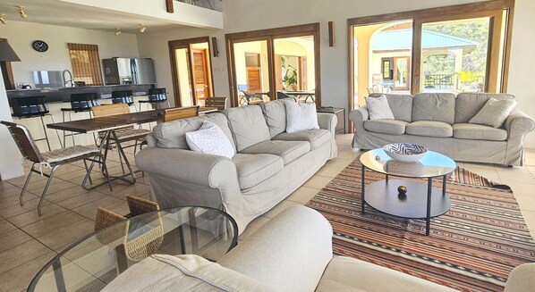 A spacious living area with a sofa, a dining table, and a kitchen in the background.