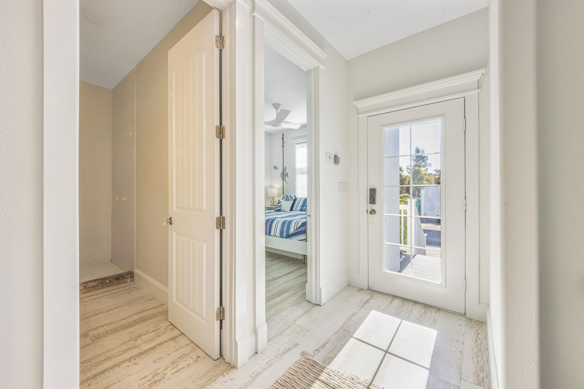Ein Flur mit einer Tür zu einem Schlafzimmer, das ein Bett und ein Fenster bietet.
