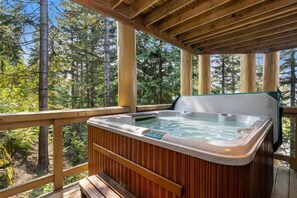 A hot tub on a wooden deck with a view of a forest. - Mountain view townhome w/ pool & hot tub (Whistler)