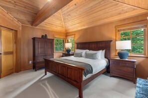 A bedroom with a wooden bed, nightstands, a dresser, and a window with a view of greenery. - Mountain view townhome w/ ski access & hot tub (Whistler)