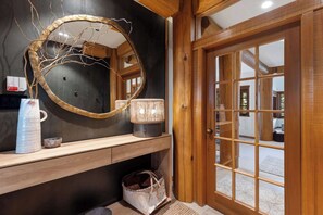 A wooden interior with a large mirror, a vase, and a lamp on a wooden console. - Mountain view townhome w/ ski access & hot tub (Whistler)