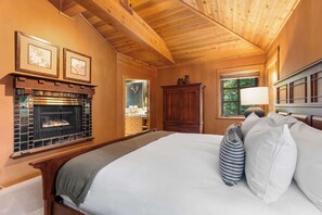 Una camera da letto con camino, soffitto in legno e un letto grande con cuscini.
