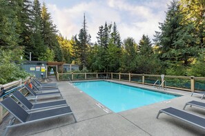 A rectangular pool with a wooden deck and lounge chairs. - Mountain view townhome w/ ski access & hot tub (Whistler)
