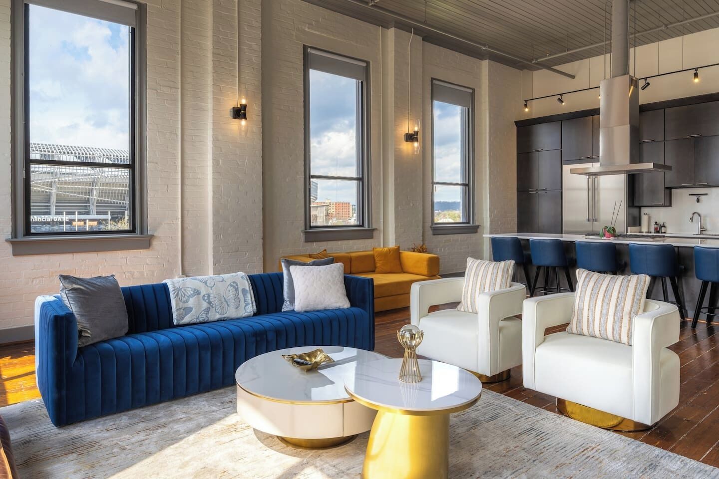 Un salon moderne avec un canapé bleu, des fauteuils blancs et une table basse ronde.