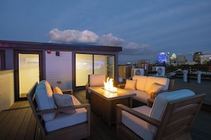 A rooftop terrace with a fire feature, seating, and a city skyline view. - Luxury 6BR Retreat w Rooftop Deck at TQL Stadium (Cincinnati)