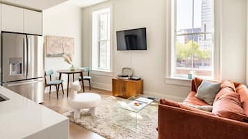 A modern apartment with a kitchen, dining area, living room, and a large window with a city view.