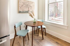 A dining area with a round wooden table, two light blue chairs, a vase with pampas grass, and a painting on the wall. - Centrally Located, Free Garage Parking! (Cincinnati)