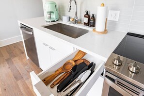 A kitchen with a dishwasher, a coffee maker, a sink, and a stove. - Centrally Located, Free Garage Parking! (Cincinnati)