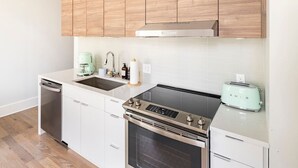 Eine kleine Küche mit Geschirrspüler, einem Herd mit Backofen, einem Toaster und Holzschränken.