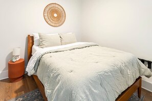 A bedroom with a bed, a bedside table with a lamp, and a wall hanging. - Centrally Located, Free Garage Parking! (Cincinnati)
