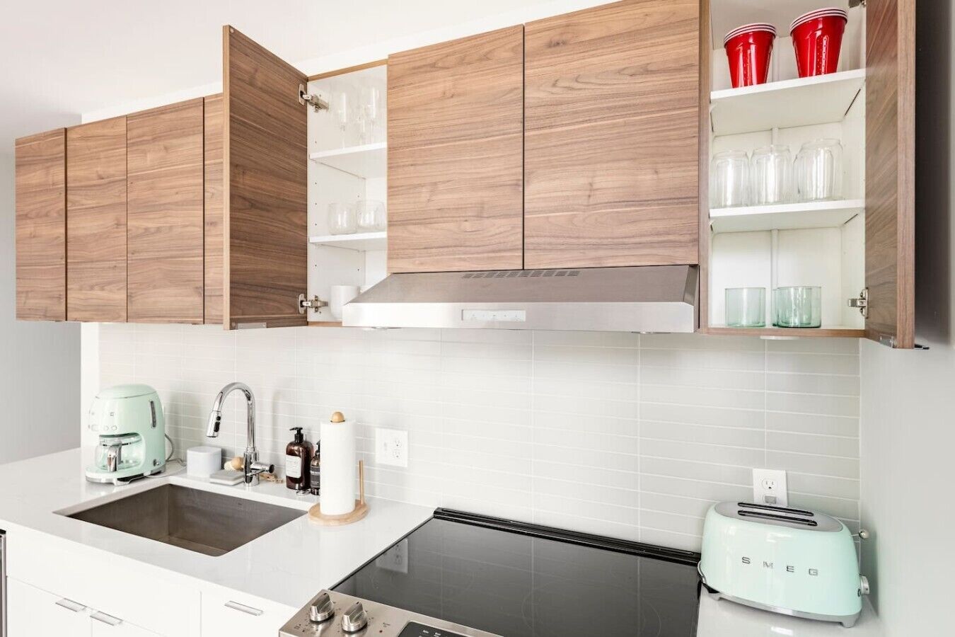 A modern kitchen with wooden cabinets, a built-in oven, a coffee maker, and a toaster.