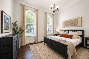 A bedroom with a bed, bedside tables, a dresser, and a window with curtains. - Lux Historic 2BR near Stadiums, Downtown (Cincinnati)