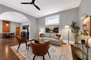 A modern living room with a sofa, chairs, a coffee table, and a dining area with a table and chairs. - Lux Historic 2BR near Stadiums, Downtown (Cincinnati)